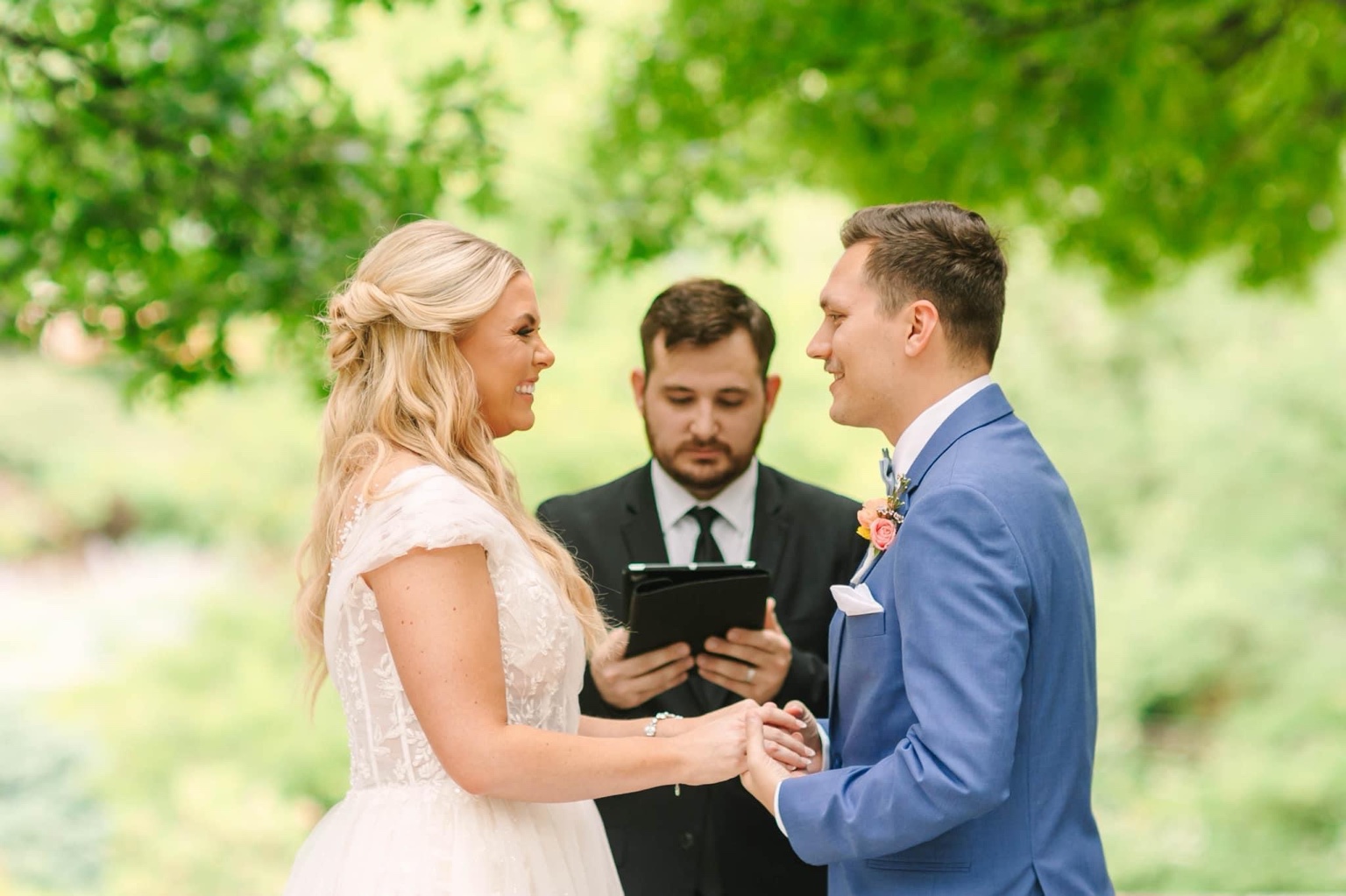 A couple smiling at each other while Eric officiates their outdoor ceremony