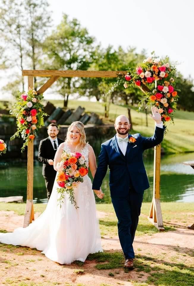 A smiling newly married couple walking away from their outdoor ceremony