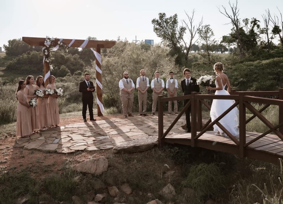 A bride walking toward the groom and wedding party at an outdoor ceremony